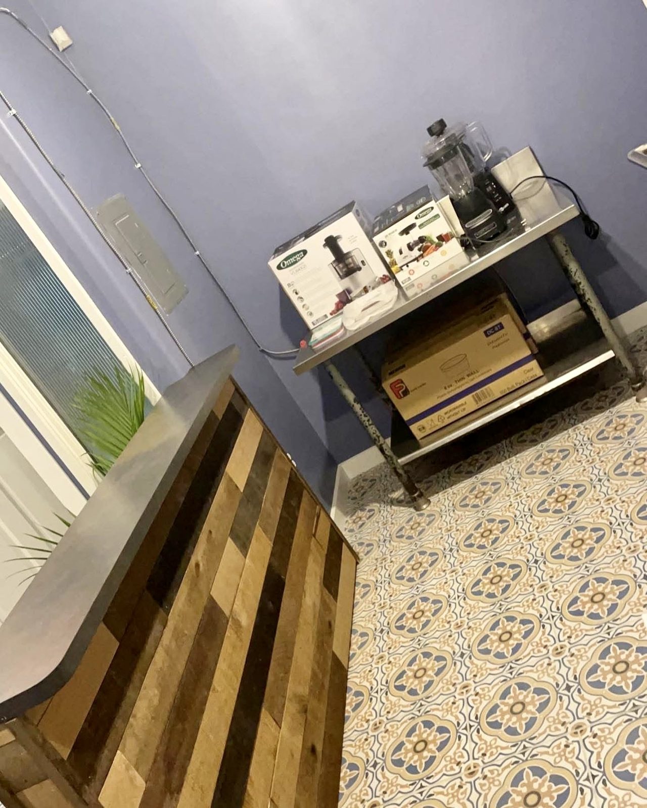 Stainless prep table and counter equipment beside the bar, encaustic tile running underneath