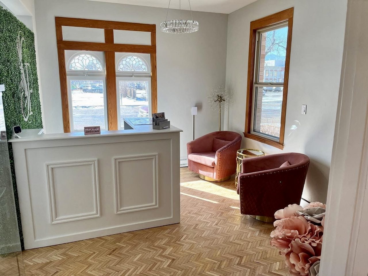 Salon reception with a paneled desk, restored herringbone parquet floor and a chandelier