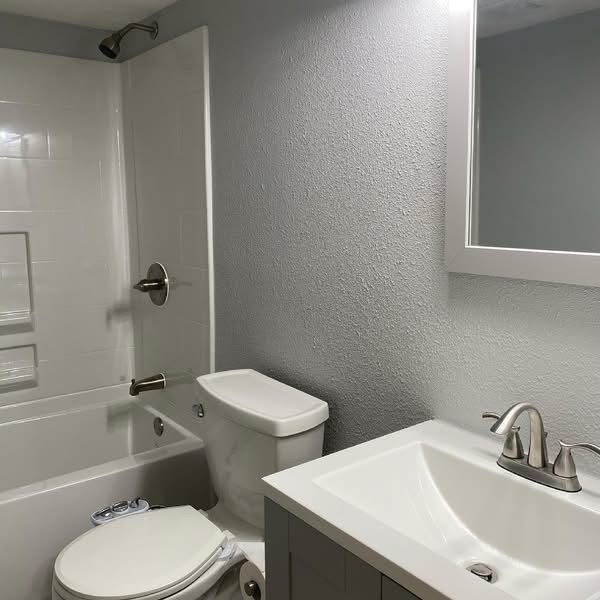 Unit bathroom with a one-piece tub and shower surround, toilet and vanity