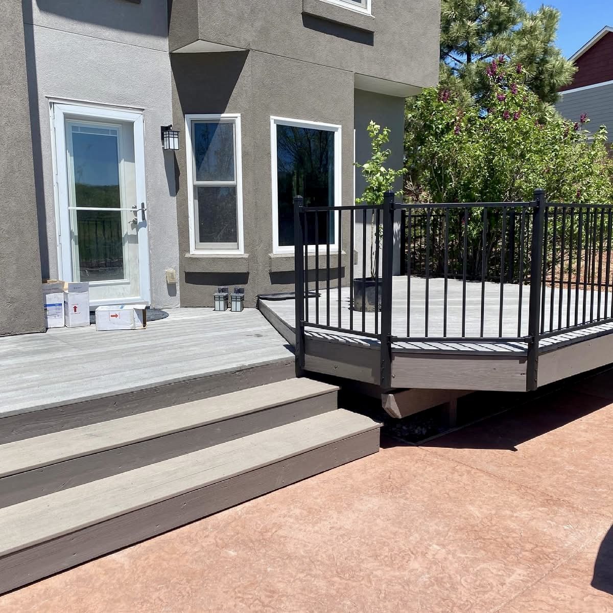 Composite deck with black metal railing and stairs down to a concrete patio