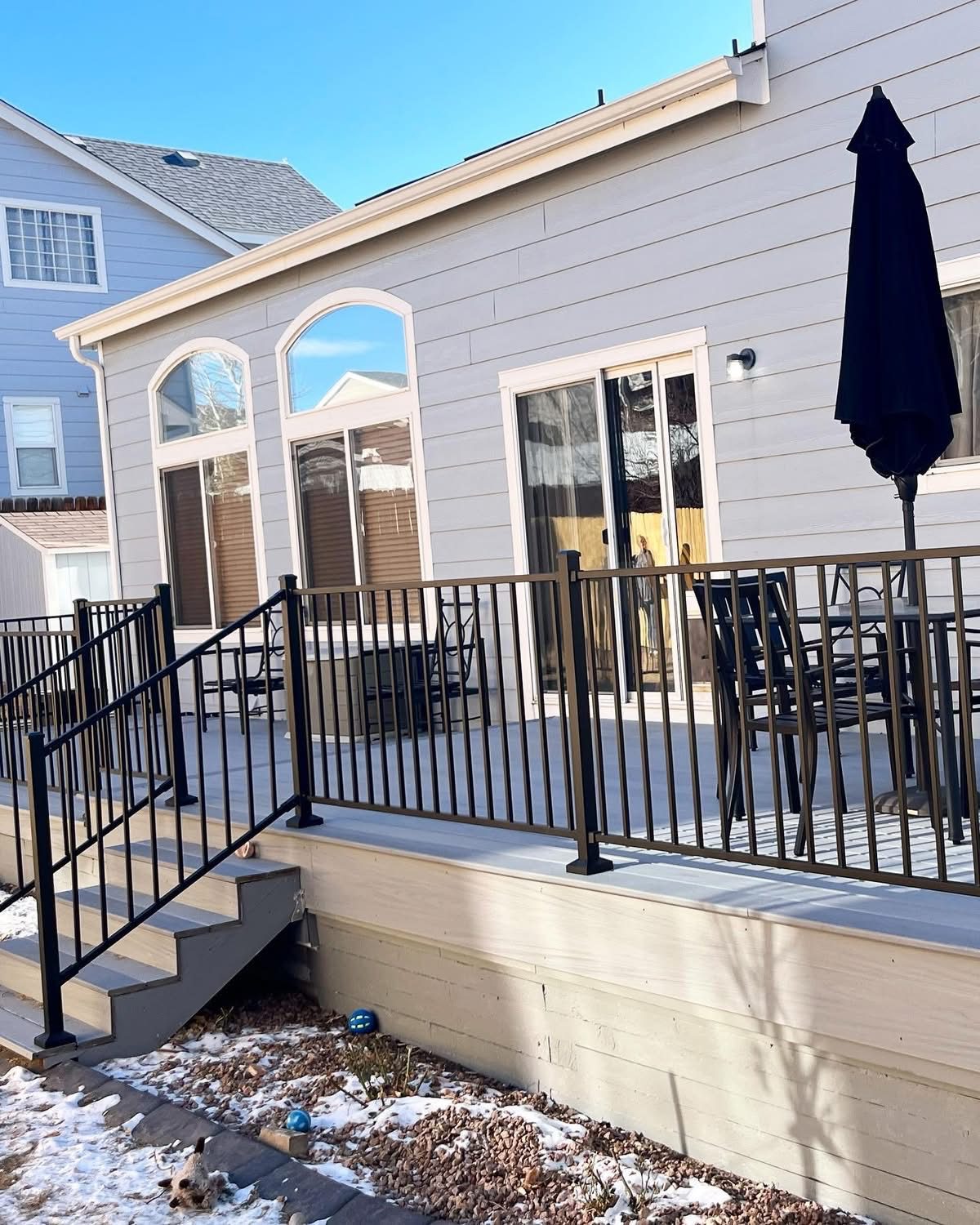 Composite deck with black metal railing, sliding patio doors and outdoor furniture