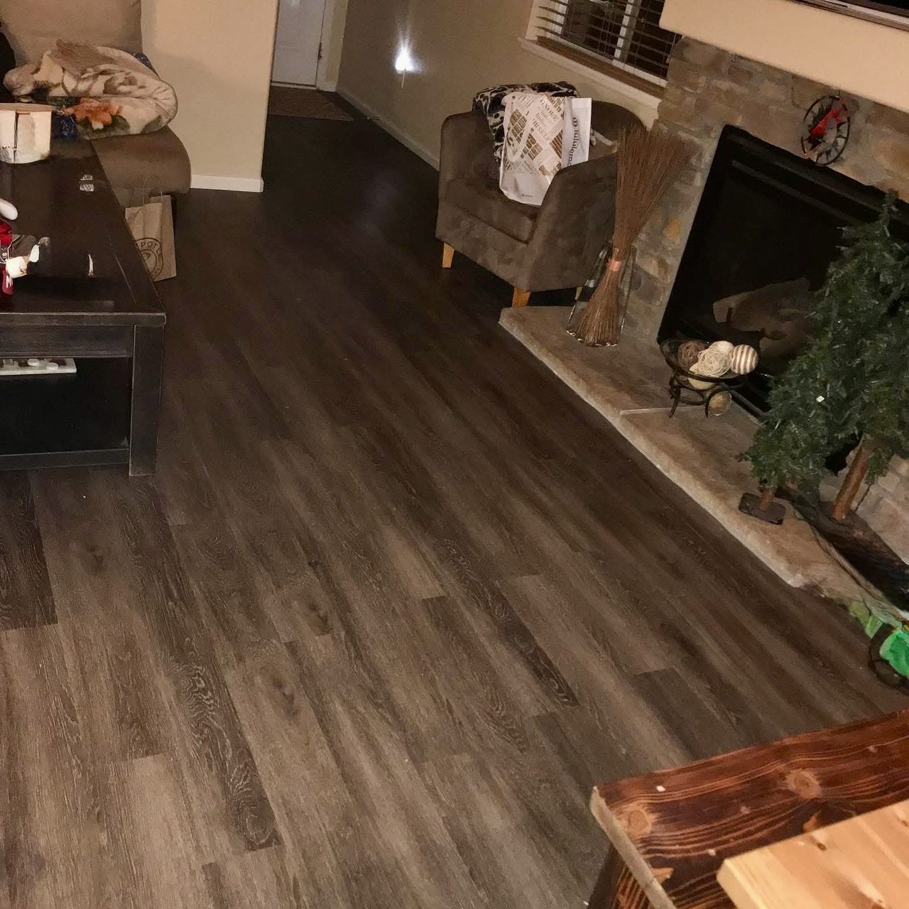 Dark luxury vinyl plank flooring in a living room with a stone fireplace