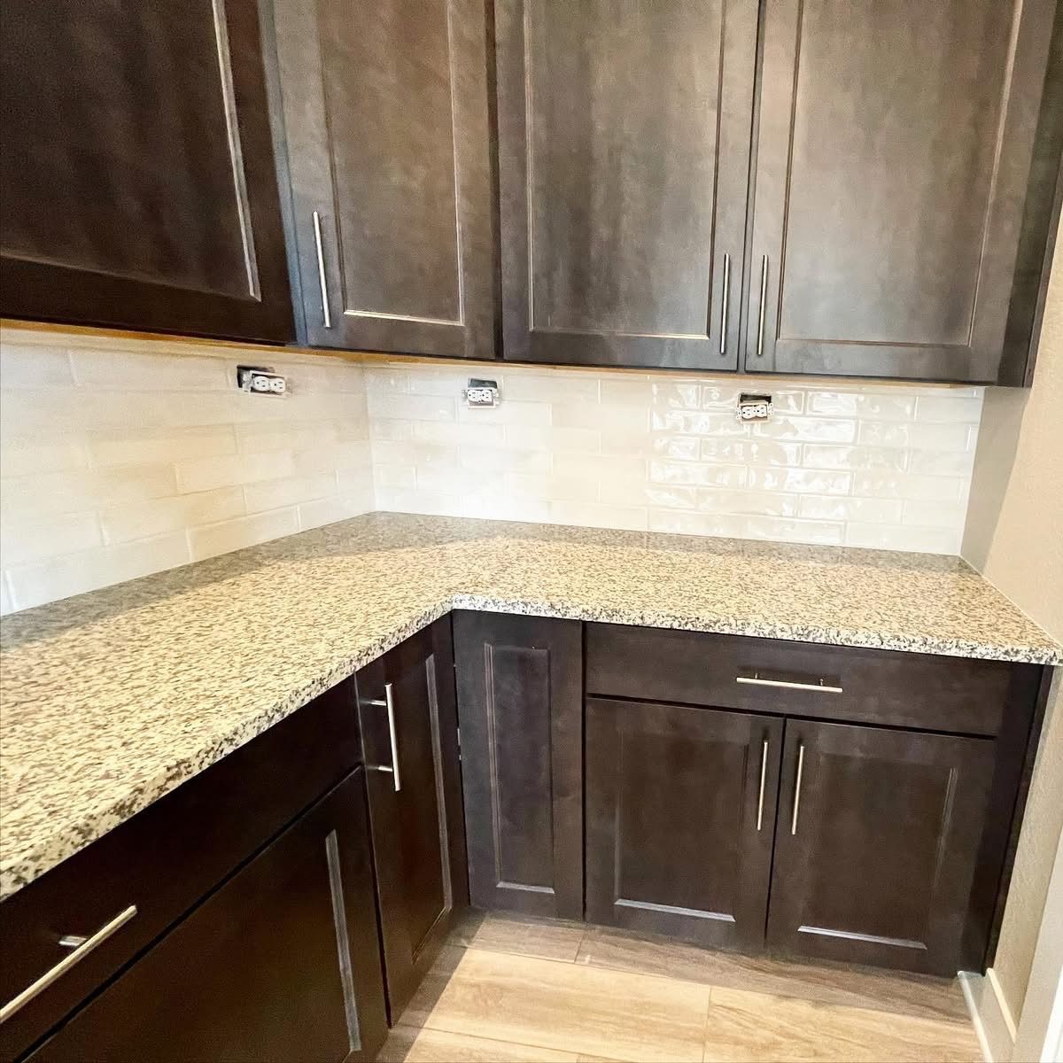Espresso kitchen cabinets with granite countertops, tile backsplash and under-cabinet lighting