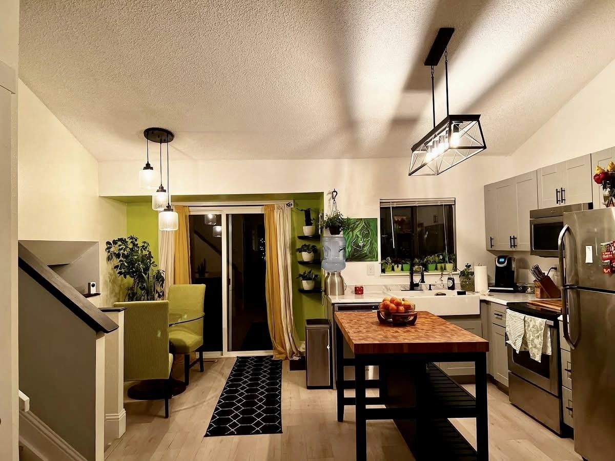 Open kitchen and dining area with a butcher-block island, pendant lighting and stainless appliances