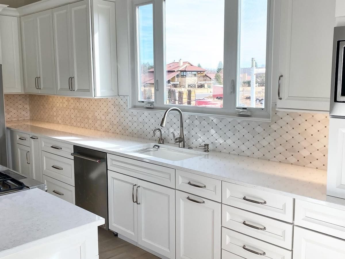 Finished kitchen with white shaker cabinets, quartz countertops, patterned tile backsplash and an undermount sink